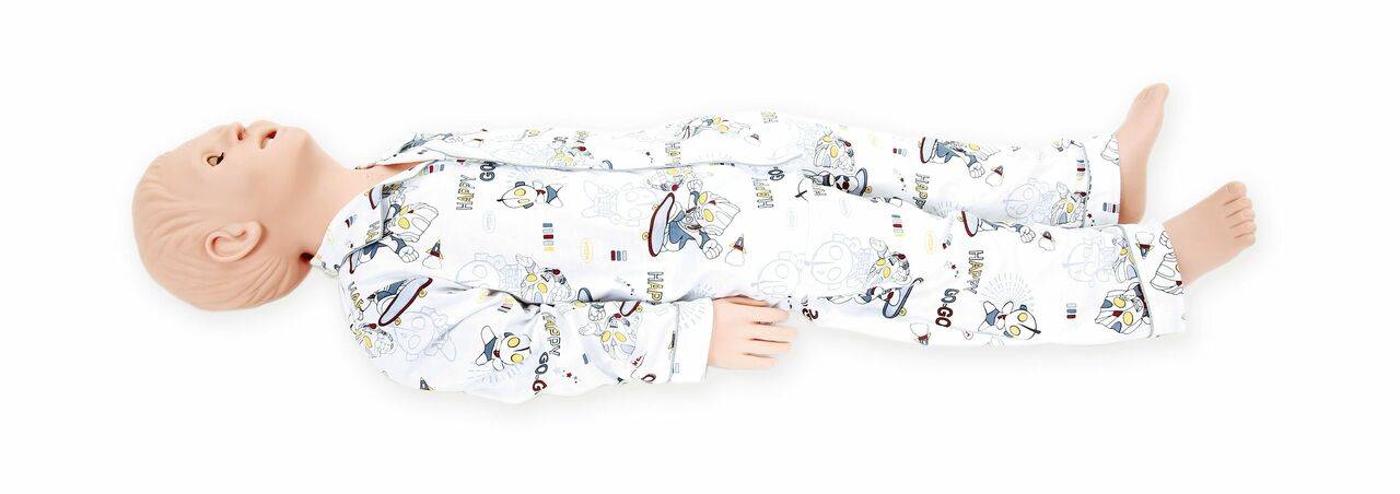 A baby lies on a white surface wearing a white, patterned sleeper.