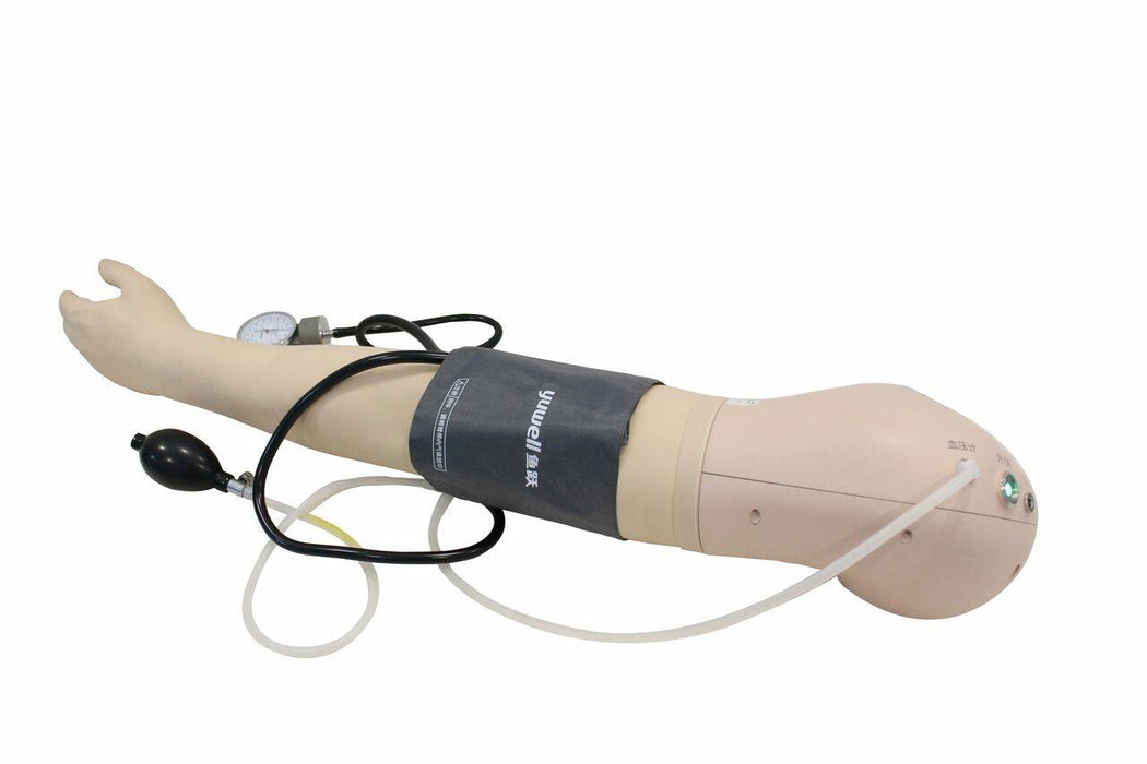 A blood pressure cuff is wrapped around a mannequin arm; a sphygmomanometer and tubing are attached. The setup rests on a plain, light background.