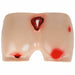 A medical training pad simulates various wounds—a deep gash, abrasions, and puncture wounds—on a pale skin-tone surface.