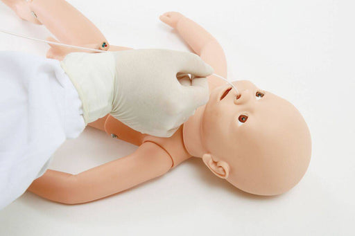 A gloved hand inserts a tube into a baby mannequin's nose. The mannequin lies supine on a white surface.