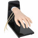 A realistic artificial hand, attached to a black base, rests on a flat surface. Two tubes extend from the base near the hand's wrist.