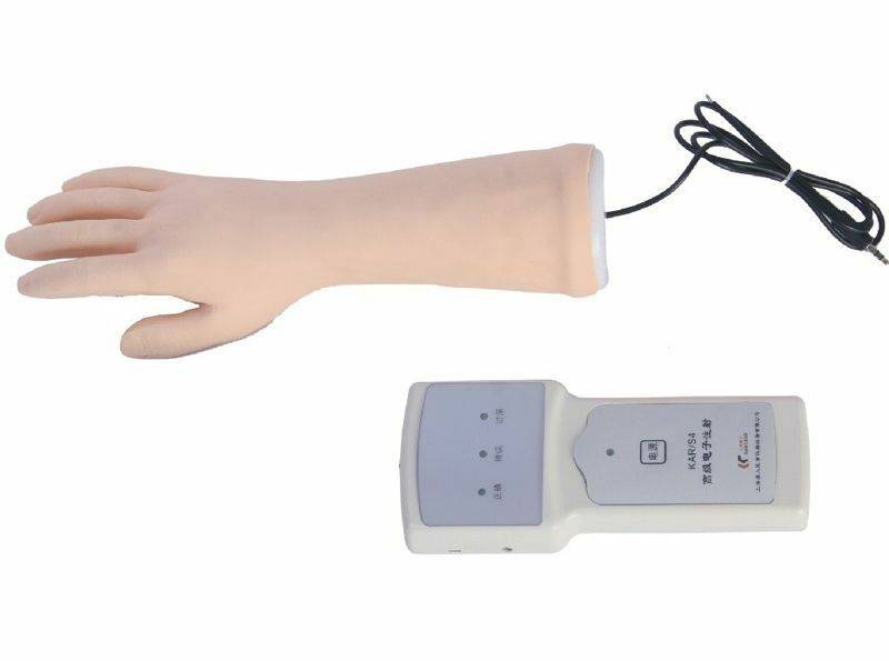 A prosthetic hand extends from its wrist, connected via a wire to a controller device that sits on the white surface.