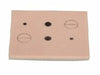 A light-brown, rectangular simulated skin pad features varying sizes and shapes of dark lesions and imperfections. The pad is set against a plain white backdrop.