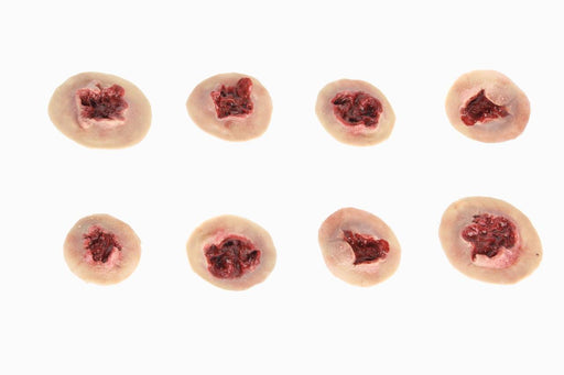 Eight artificial wounds, depicting flesh with simulated blood, are arranged on a white background.