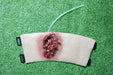 A simulated wound, featuring a laceration and tubing, rests on artificial turf.