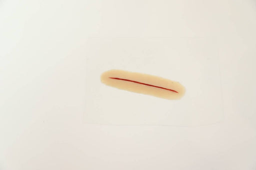 A prosthetic wound, resembling a cut, lies on a white surface.