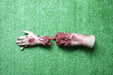 A severed, bloody arm lies on artificial turf; the hand is outstretched.
