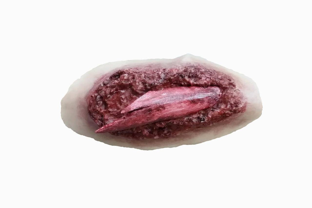 A simulated laceration, featuring a deep red wound with a protruding piece of flesh, rests on a pale background.