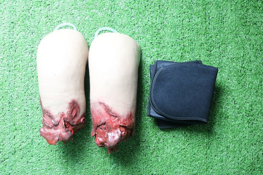 Two prosthetic legs, appearing injured, rest on artificial turf alongside a folded black fabric item.
