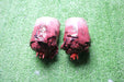 Two artificial severed limbs, resembling bloody, fleshy stumps, rest on artificial turf.