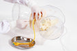 Hands in gloves insert a yellow catheter into a female anatomical model inside of a clear container with a steel tray, which has the text "30ml" written on the side of it, sitting below.