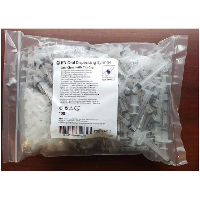One hundred 3ml oral dispensing syringes with tip caps are contained within a plastic bag. The syringes are clear and appear to be individually packaged. The bag includes a label with product information and a reference number: REF 305220.