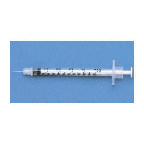 A 5 ml syringe rests on a blue surface. The syringe is clear plastic with black markings.