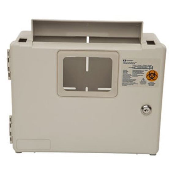 A beige sharps container has slots at the top and a central opening with horizontal and vertical guides; a warning label with a biohazard symbol is affixed to its side.